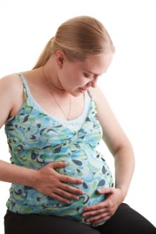 a pregnant women holding her tummy and feeling her baby kicking